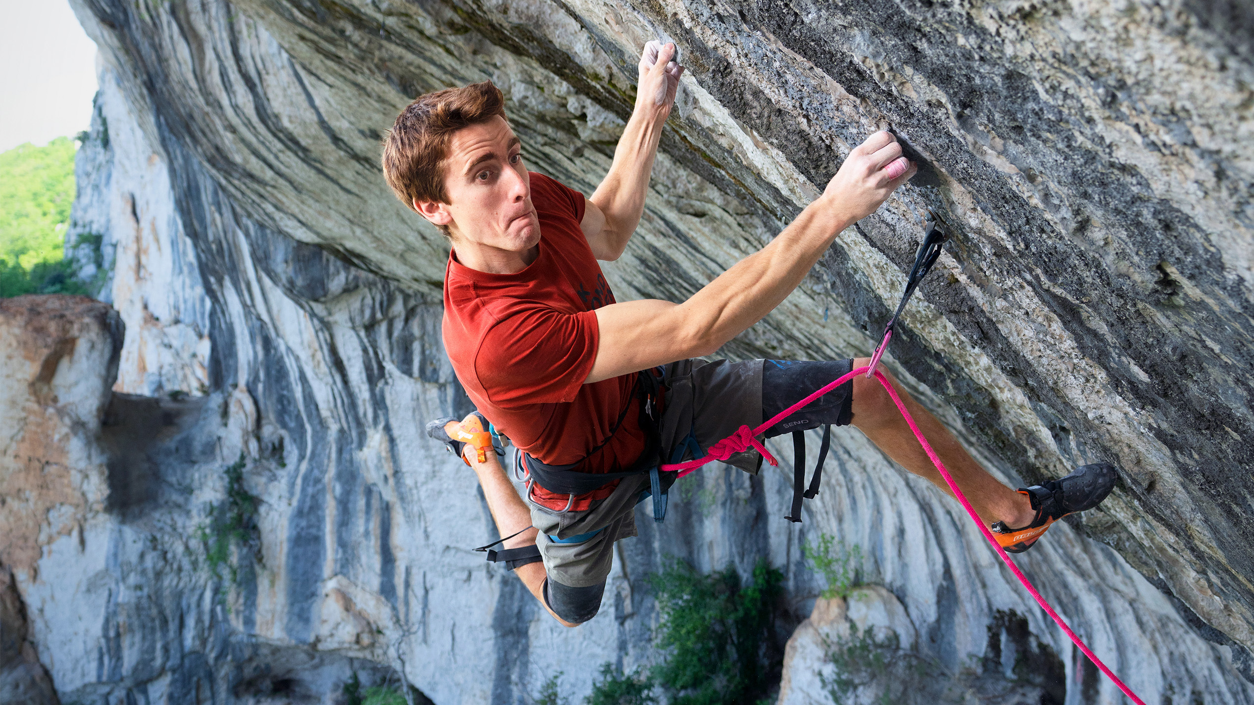 Mann klettert an einem steilen Felshang