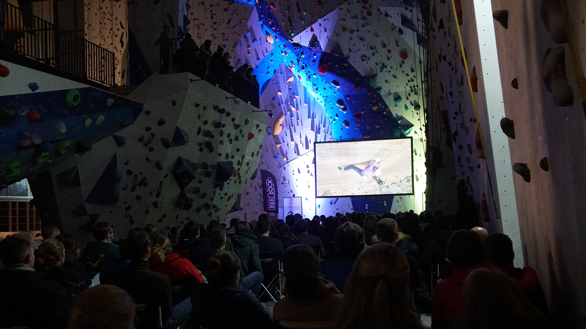 Kletterhalle mit aufgebauter Leinwand und großem Publikum