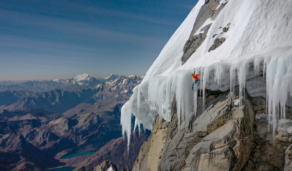 Man climbing in high air on a beg with snow and icicles